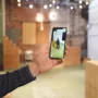 A hand holding a smartphone that displays AR in a space that has a digital twin