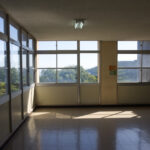 A large window looking on a green mountain range from a Japanese school