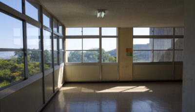A large window looking on a green mountain range from a Japanese school