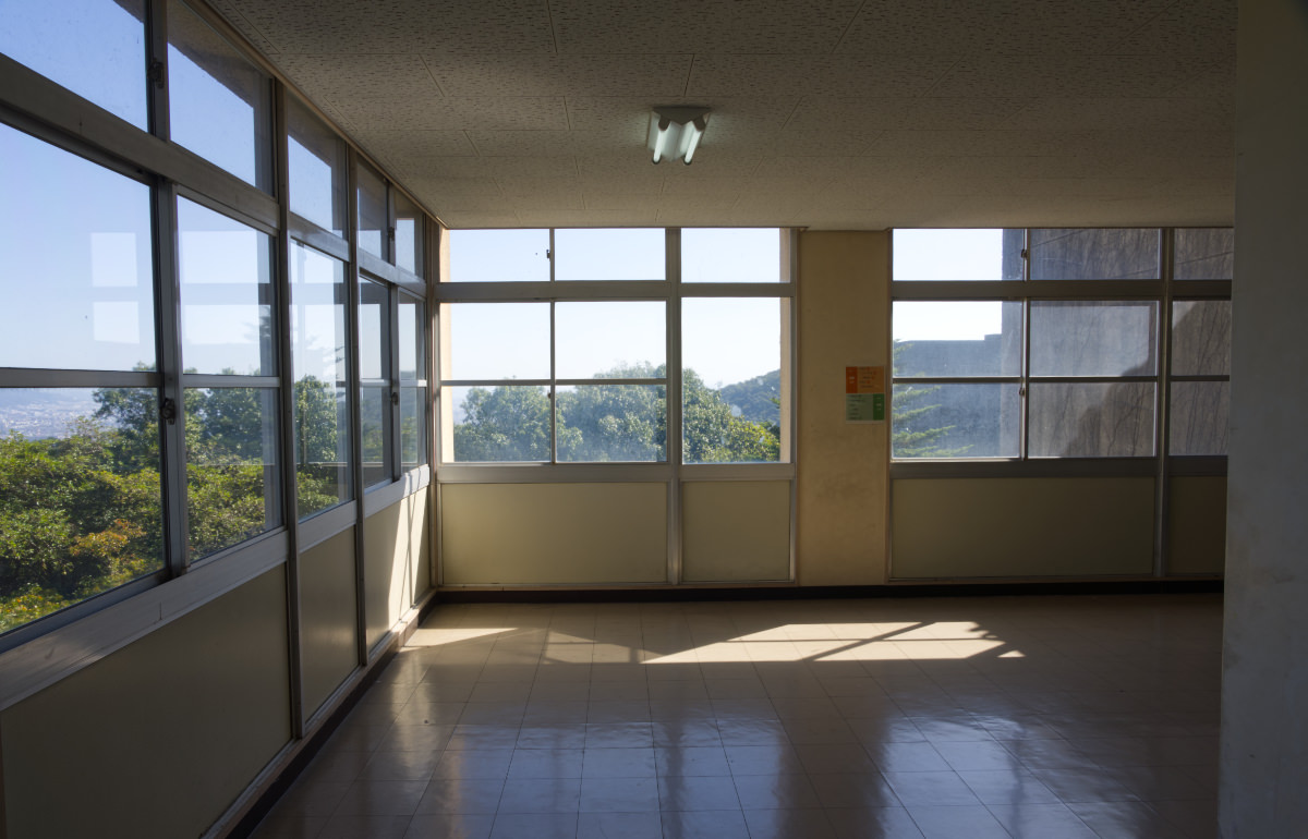 A large window looking on a green mountain range from a Japanese school